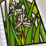 a finished center panel of the in-progress window that has two white Irises surrounded by light and dark green leaves going in all directions