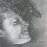 profile of a face scrunched against camera with clenched teeth, tightly squinted eyes, and hair swooshing up and out in several directions