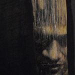 nose, lips and strong brow emerging from the darkness on a curved wooden branch that has been mounted to a black flat wooden panel