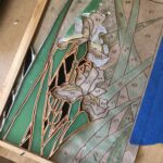 the sketch of the design is taped down and copper-foiled pieces of glass have started being laid over their respective shapes in the sketch
