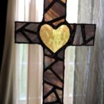 finished cross suncatcher with blue-purple angular pieces of a cross that has a bright transparent yellow heart at the center