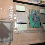 the cut pieces of the larger Iris window are being soaked to remove the brown template paper from each and then they are carefully laid out according to the design