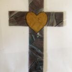 blue-purple angular pieces of a cross with a yellow heart at the center are cut and laid into their positions