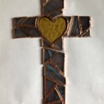 blue-purple angular pieces of a cross with a yellow heart at the center are copper-foiled and loosely laid into their positions