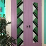the closet door glass with its stacked green triangles with dark brown bottom double stripe details and splotchy cream background are installed in a set of narrow closet doors