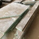 a stack of the closet door glass that is all cut, ground, and ready to have the template paper removed