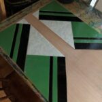 the first few green, dark brown stripes, and splotchy cream background pieces are all being laid in place in preparation for came