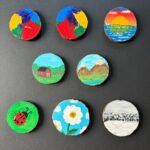 Eight rustic round live-edge coasters with various images painted on them, photographed as a group