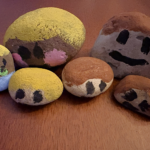 Various sizes of rock painted to be a family of six, including a baby in a diaper