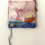 a square mixed media image of two fish, one in the water, one in a wooden boat; there are round clouds in the sky with red edges at the center where a thread swirls above the water and up into a figural shape in the boat