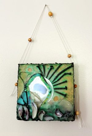 a square low-relief mixed media encaustic painting of cream, turquoise, green and ochre with the iridescent purple of muscle shells that are oriented vertically across the bottom from left to right gradually laying horizontally and appearing to float away; two pieces of similarly sized turquoise glass shards are arranged above the shells and outlined in black that mimic the black of a ray-like, radial arrangement of bent rusty nails arranged small to large and back to small around the top right edge of a circular mirror embedded slightly off-center into the teal-black encaustic medium of the bottom; there are two concave circular scoops out of the wax - one at the top left, the other down to the right of the mirror - revealing the golden wood below